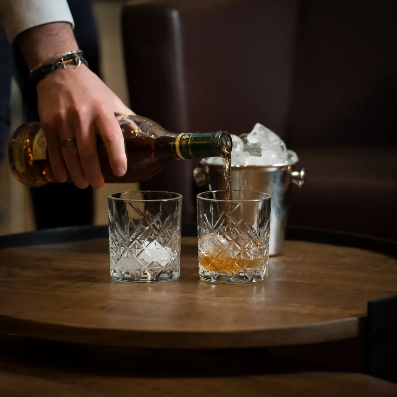 Verser du whisky dans un verre avec glaçons.