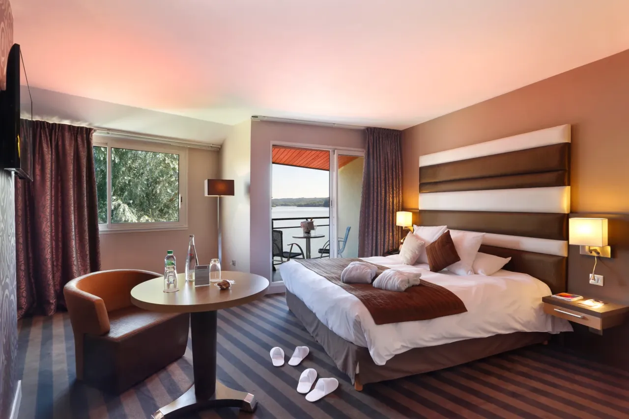 Chambre d'hôtel avec balcon et vue sur lac.