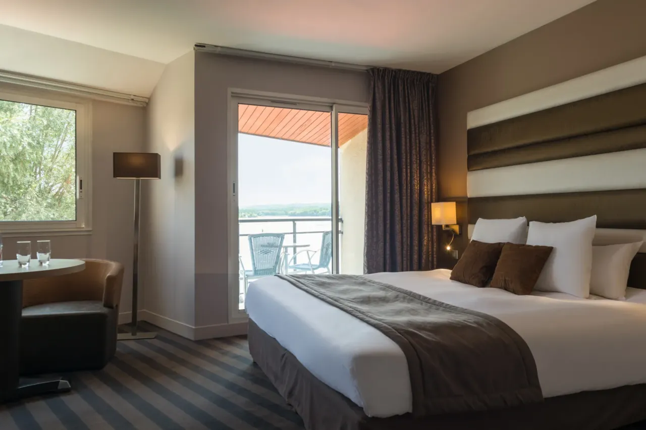 Chambre d'hôtel élégante avec balcon et vue extérieure.