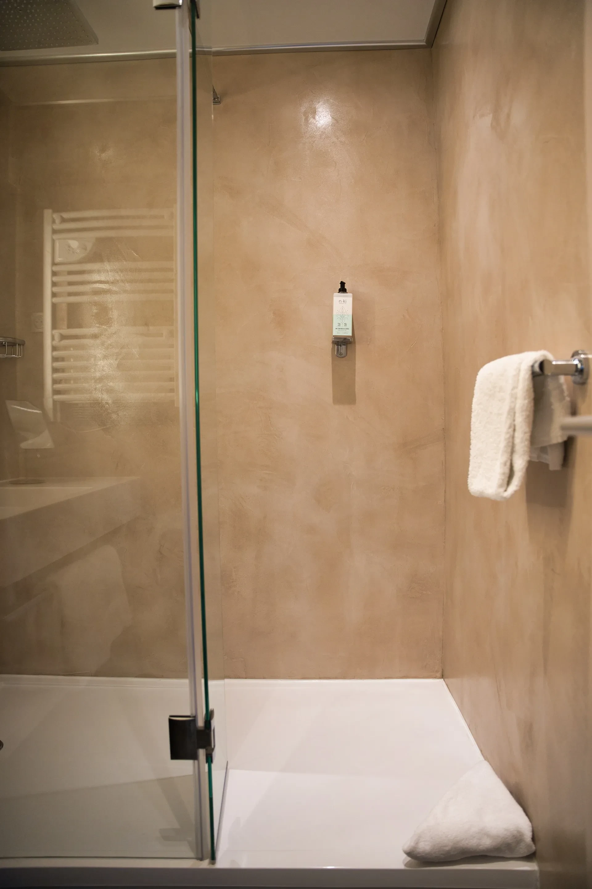 Cabine de douche moderne avec serviette blanche.