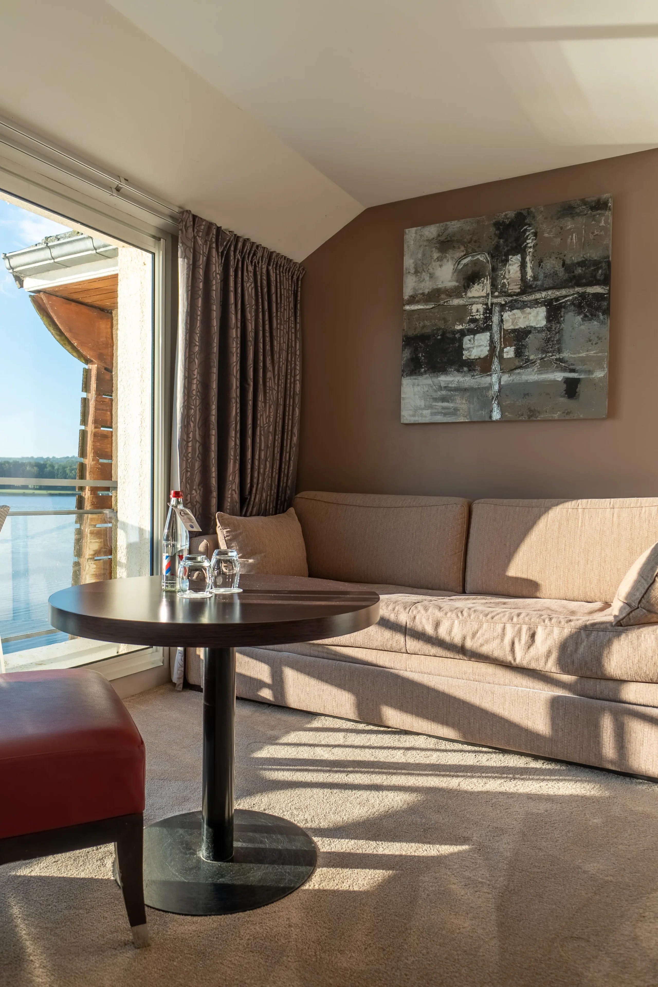 Intérieur d'une suite avec canapé confortable, table basse et lumière naturelle.