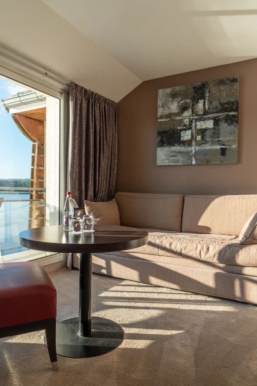 Intérieur d'une suite avec canapé confortable, table basse et lumière naturelle.