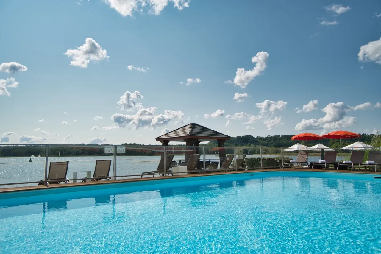 Piscine avec transats et parasols au bord du lac.