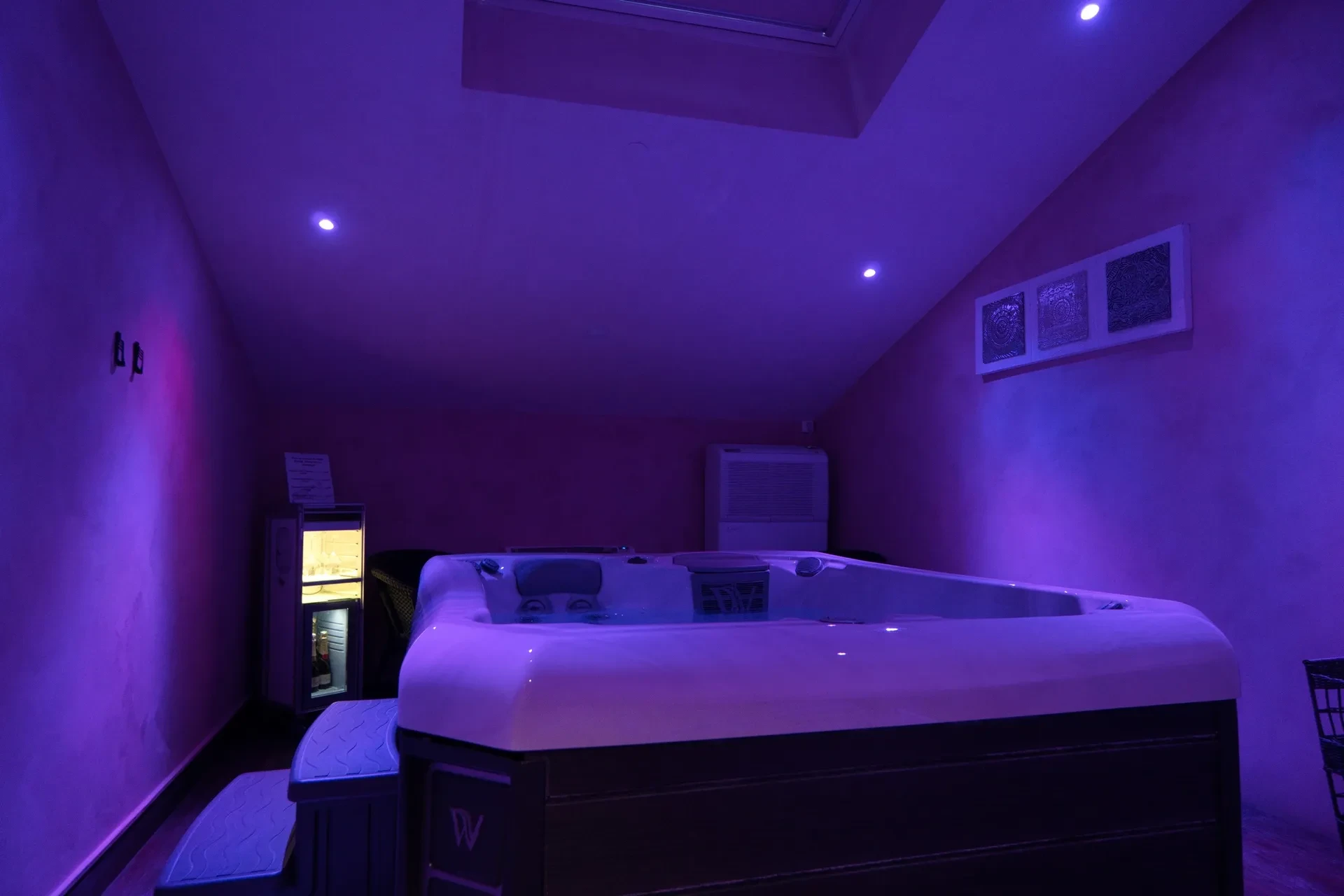 Jacuzzi dans une pièce éclairée en violet.
