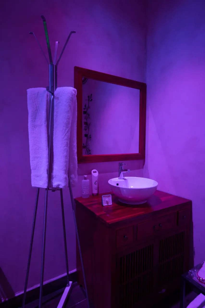 Salle de bain éclairage violet, lavabo blanc.