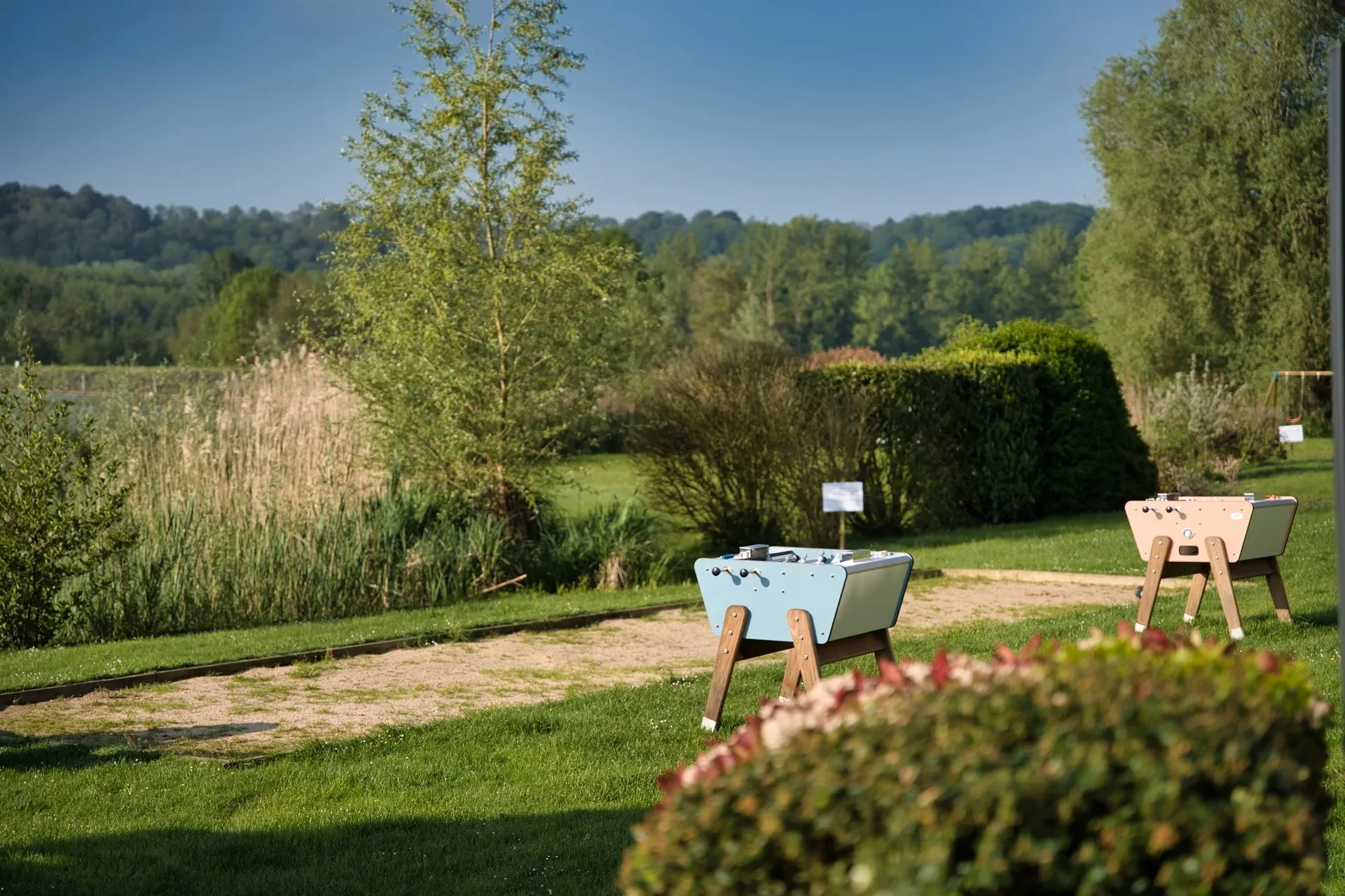 Jardin avec baby-foot en extérieur, arbres et arbustes.