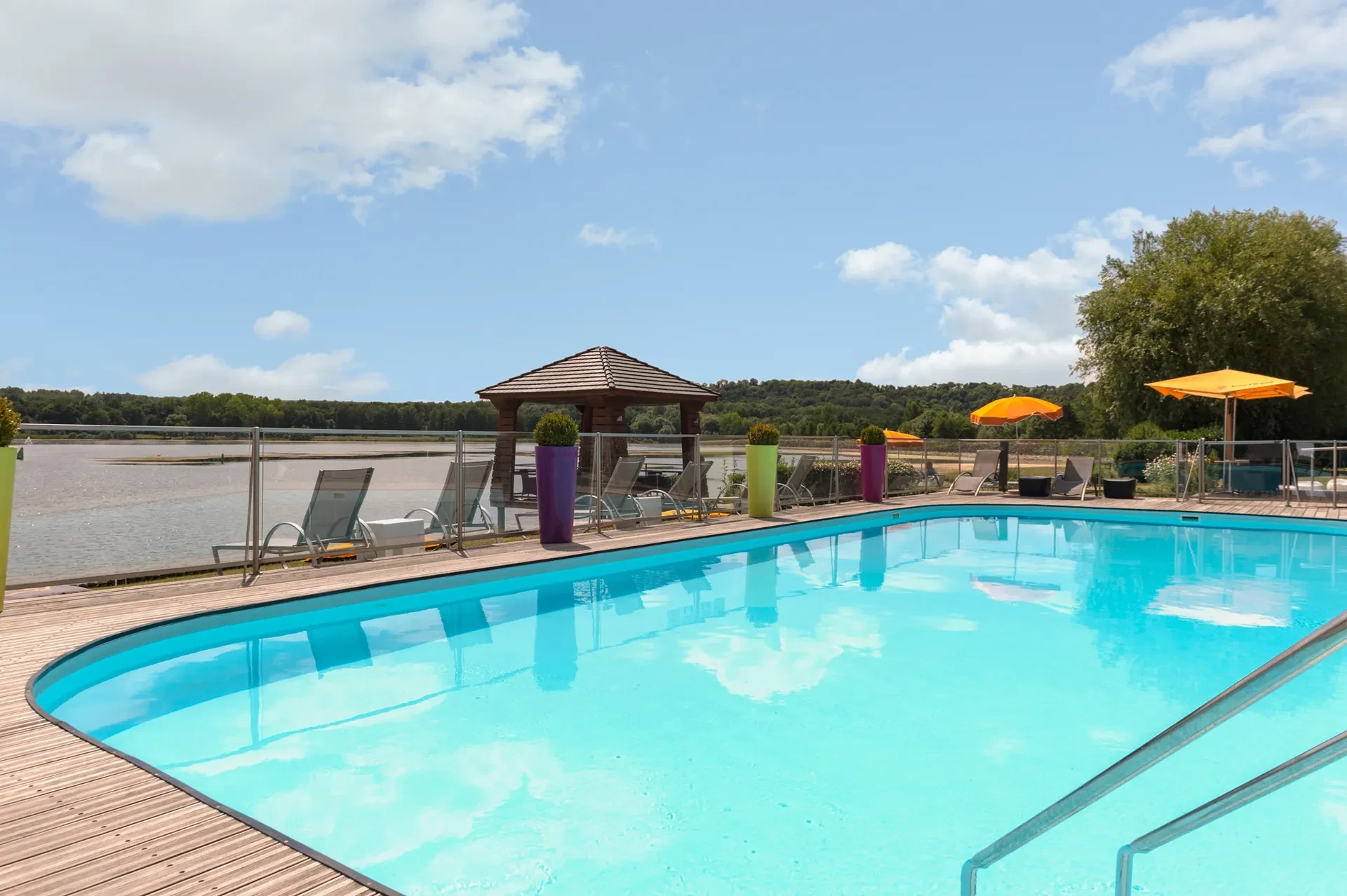 Piscine extérieure avec vue sur lac et chaises.
