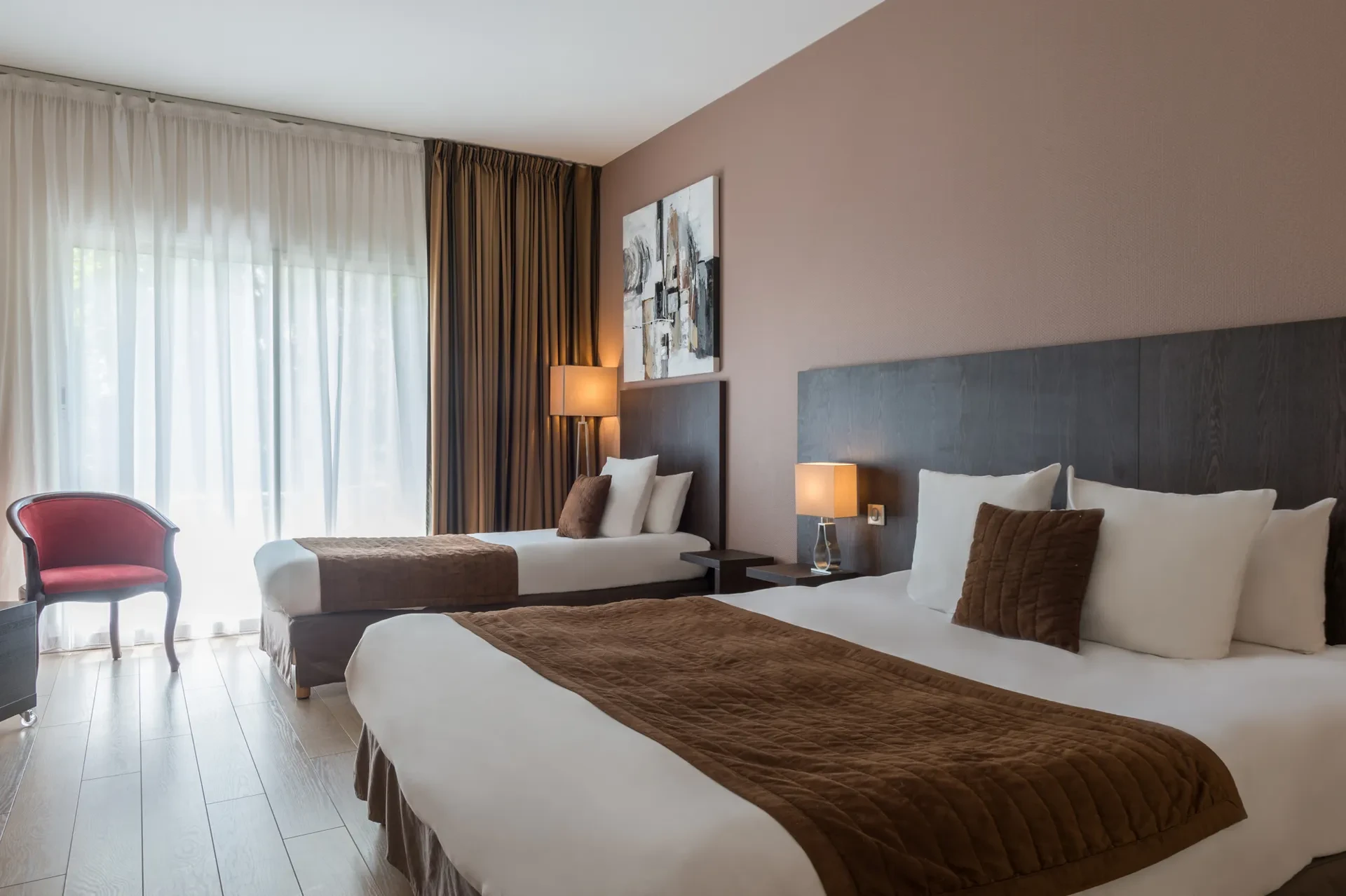 Chambre d'hôtel avec lits jumeaux et fauteuil rouge.
