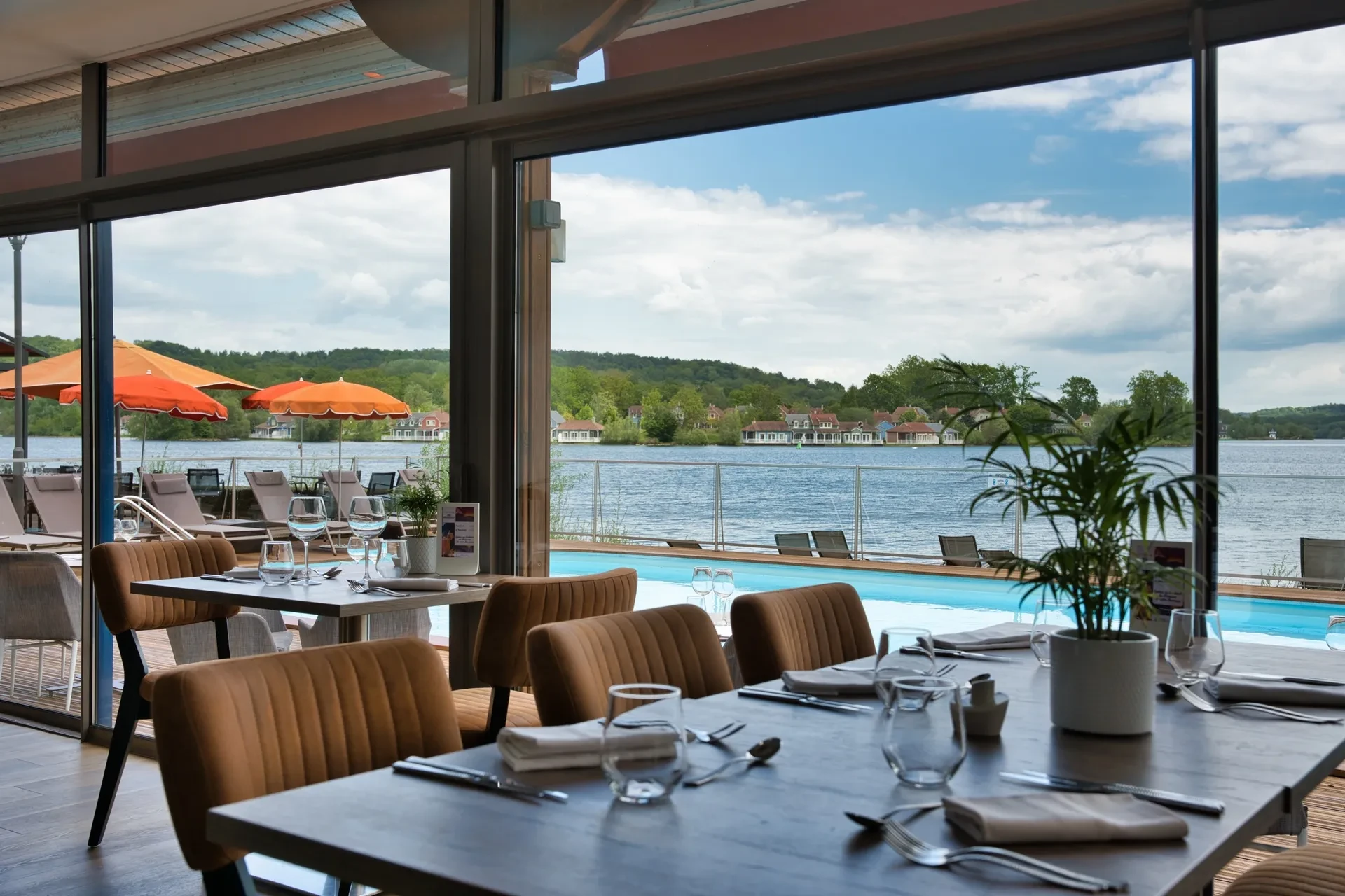 Restaurant avec vue sur lac et parasols oranges.