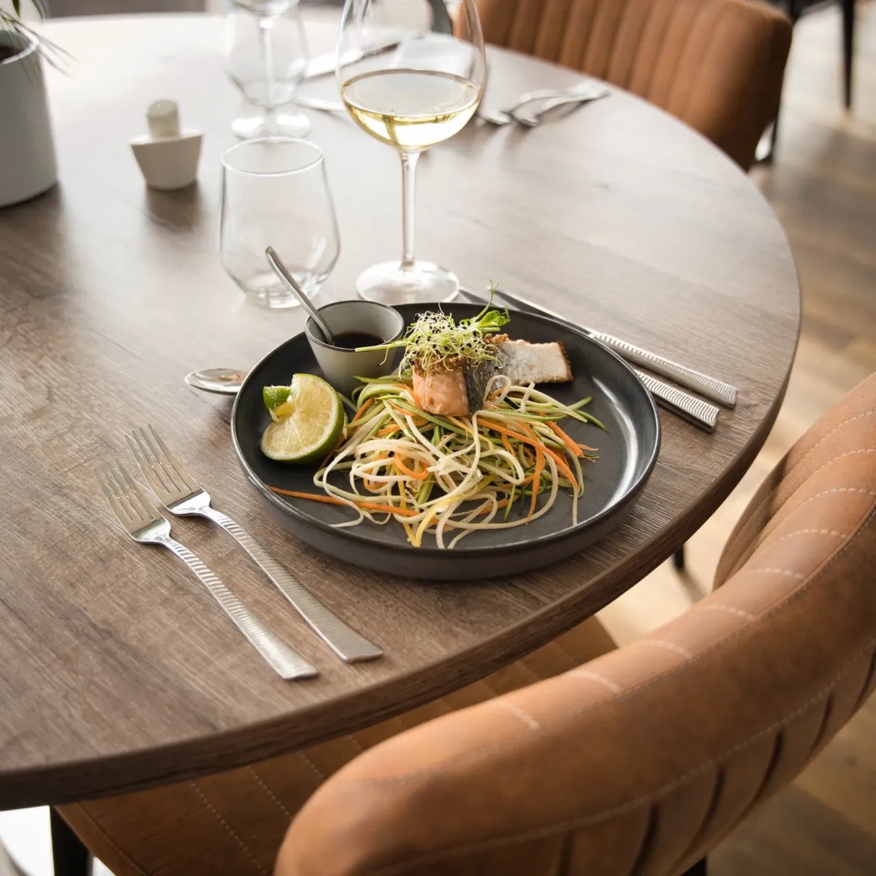 Plat gastronomique dressé sur une table en bois dans un restaurant moderne.