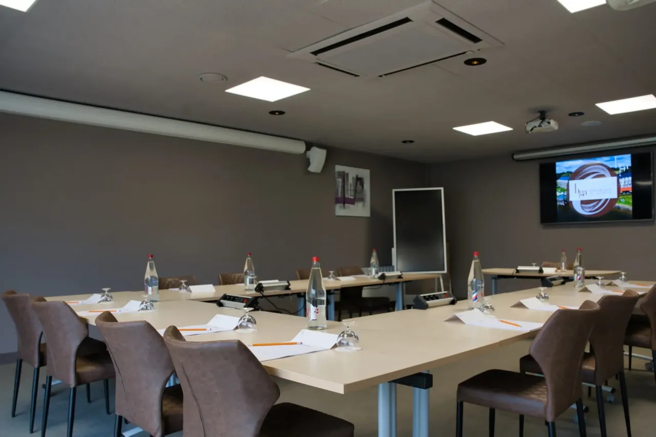 Salle de réunion moderne avec chaises et table.