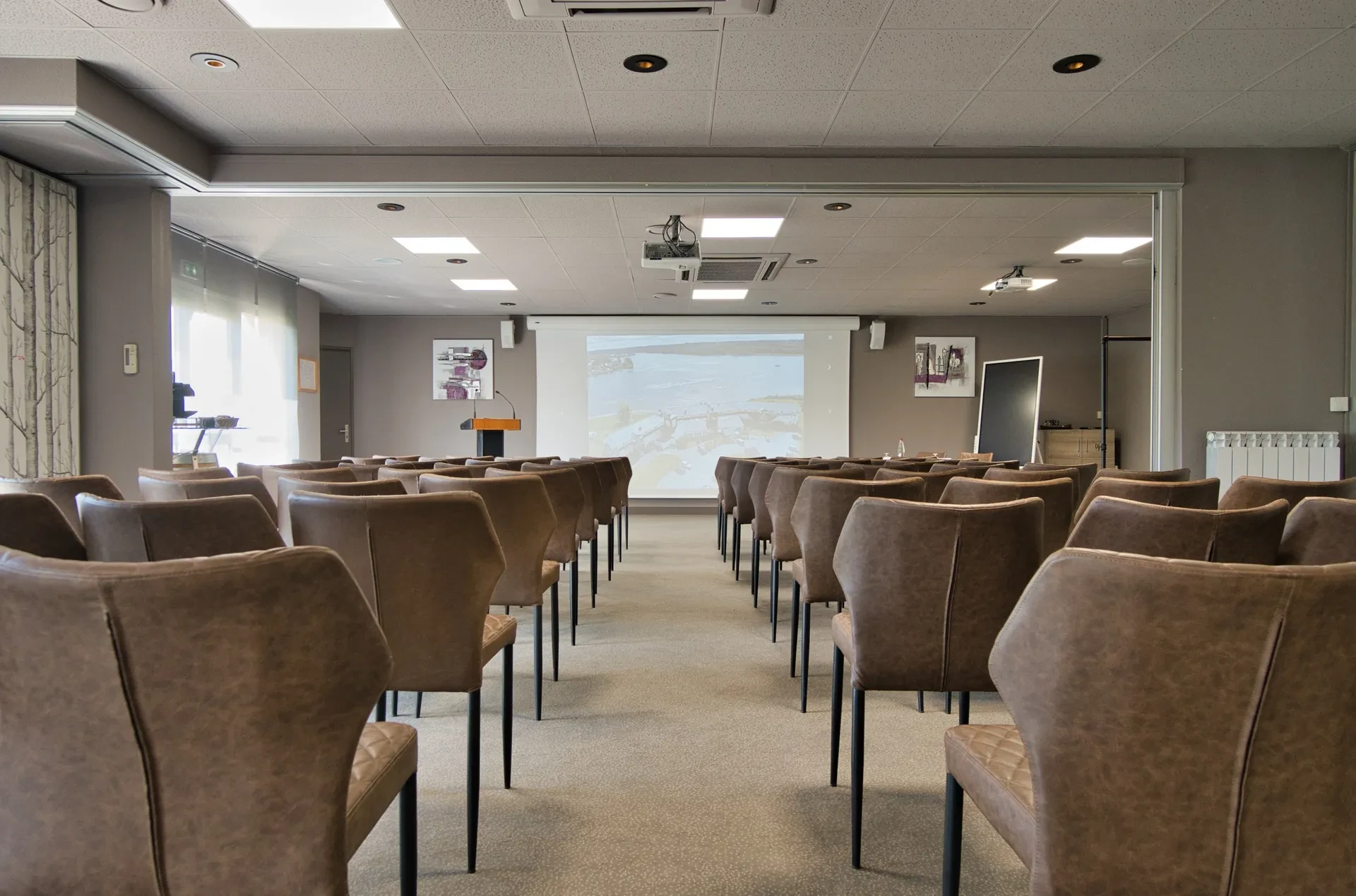 Salle de conférence vide avec écran et podium.