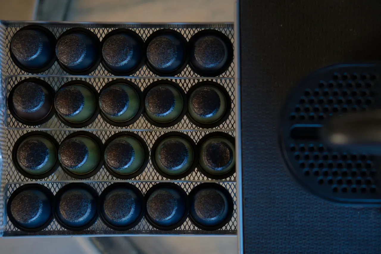Capsules de café sur une grille métallique.