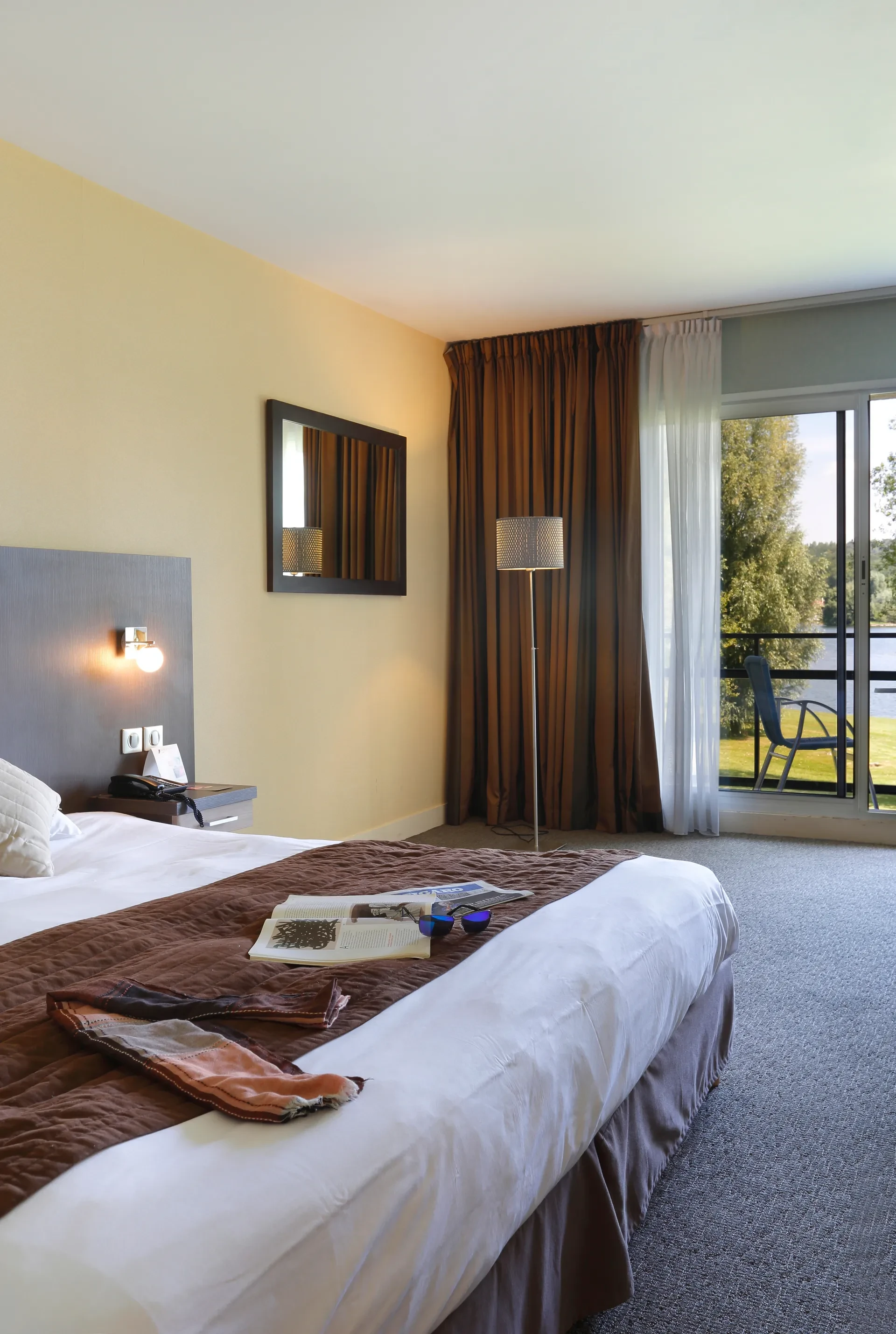 Chambre d'hôtel avec vue sur terrasse verdoyante.