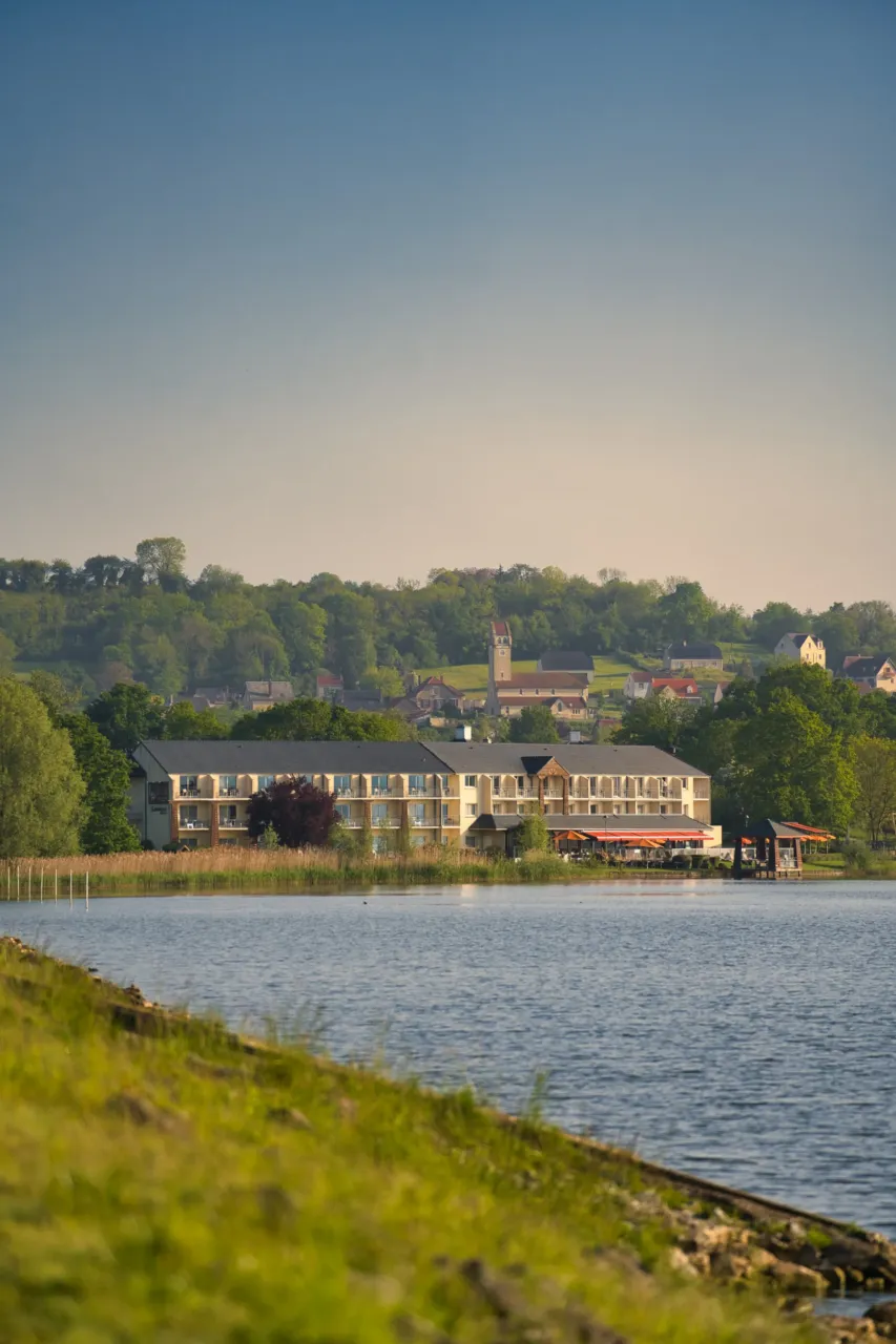 Hôtel près d'un lac avec village en arrière-plan.